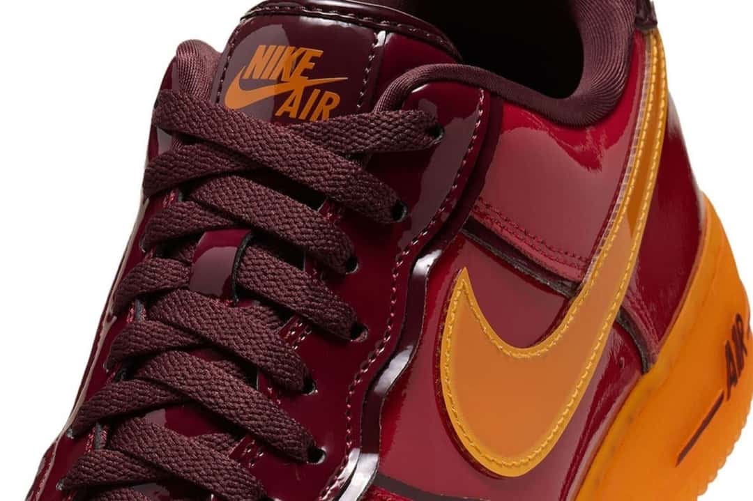 Detalle del Nike Air Force 1 Iron Man con el logo Nike Air naranja en la lengüeta, los cordones bordó y el Swoosh naranja sobre el charol rojo