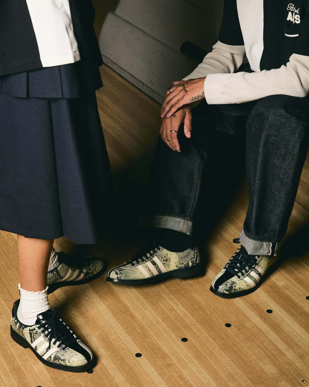 Campaña del Brain Dead x adidas Samba Bowling en una pista de bowling: dos personas con ropa de estilo bolero, una con pollera azul y medias blancas y otra con jean arremangado, ambas con el modelo Snakeskin puesto