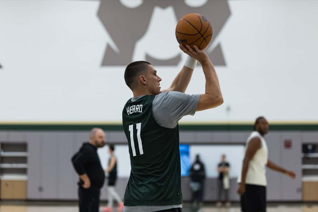 Tyler Herro, con la musculosa verde número 11 de los Bucks, lanza en la práctica del día del partido en Milwaukee