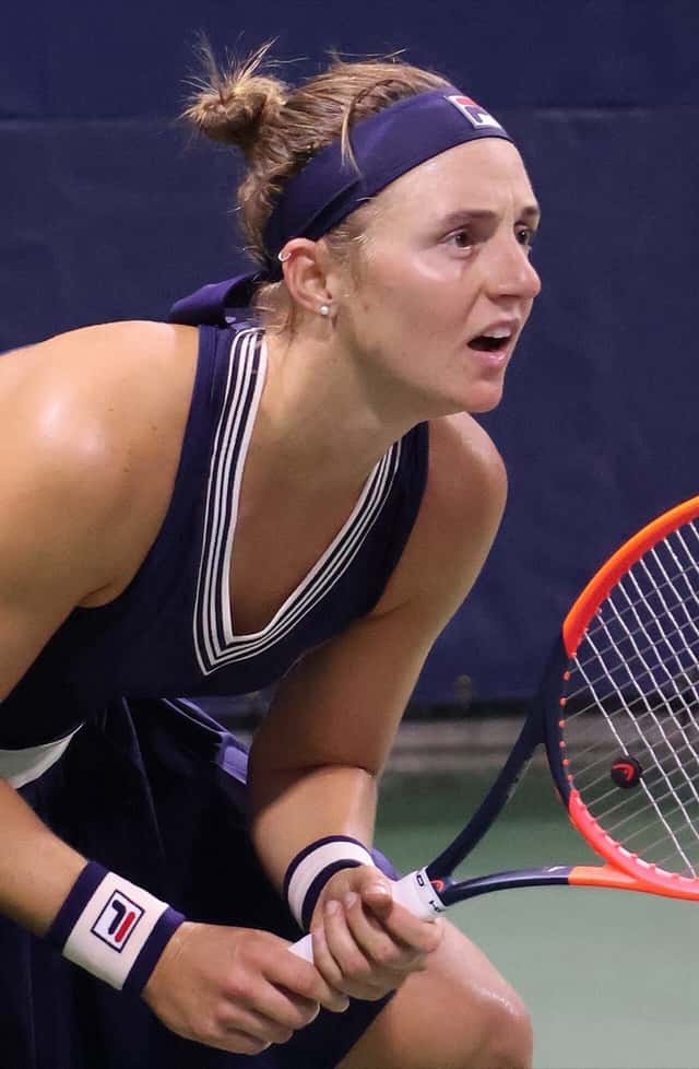 Foto de archivo: Nadia Podoroska, con vincha y vestido azul oscuro, en posición de devolución durante un partido nocturno del US Open 2023