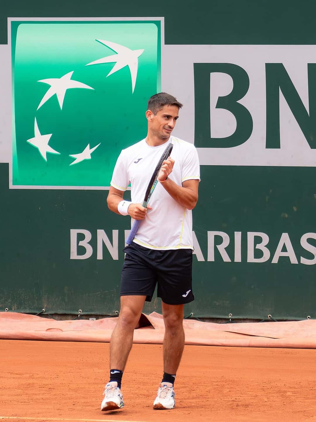 Foto de archivo: Mariano Navone, con remera blanca y short negro, en una cancha de polvo de ladrillo de Roland Garros, con la raqueta en la mano
