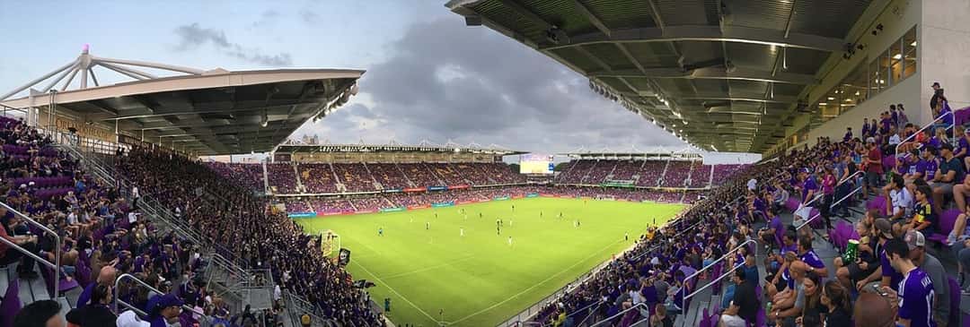 Las tribunas del estadio de Orlando City llenas de hinchas con camisetas violetas, en una vista panorámica desde una platea lateral; foto de archivo de 2018 (foto: Porsche997SBS, Wikimedia Commons, licencia CC BY-SA 4.0)