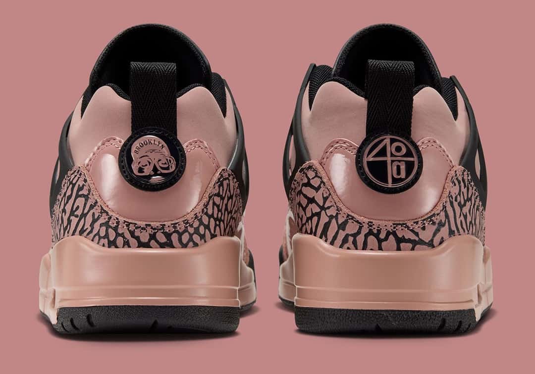 Talones de la Jordan Spizike Low Rust Pink, con el tirador negro, el logo redondo en el talón y el estampado cemento sobre el charol rosa