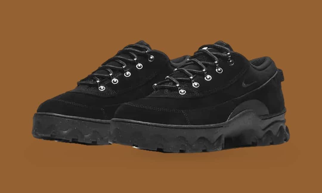 Par de Nike Air Lahar Low negras de gamuza, con Swoosh negro, ojales metálicos y suela negra de taco pesado, sobre fondo marrón