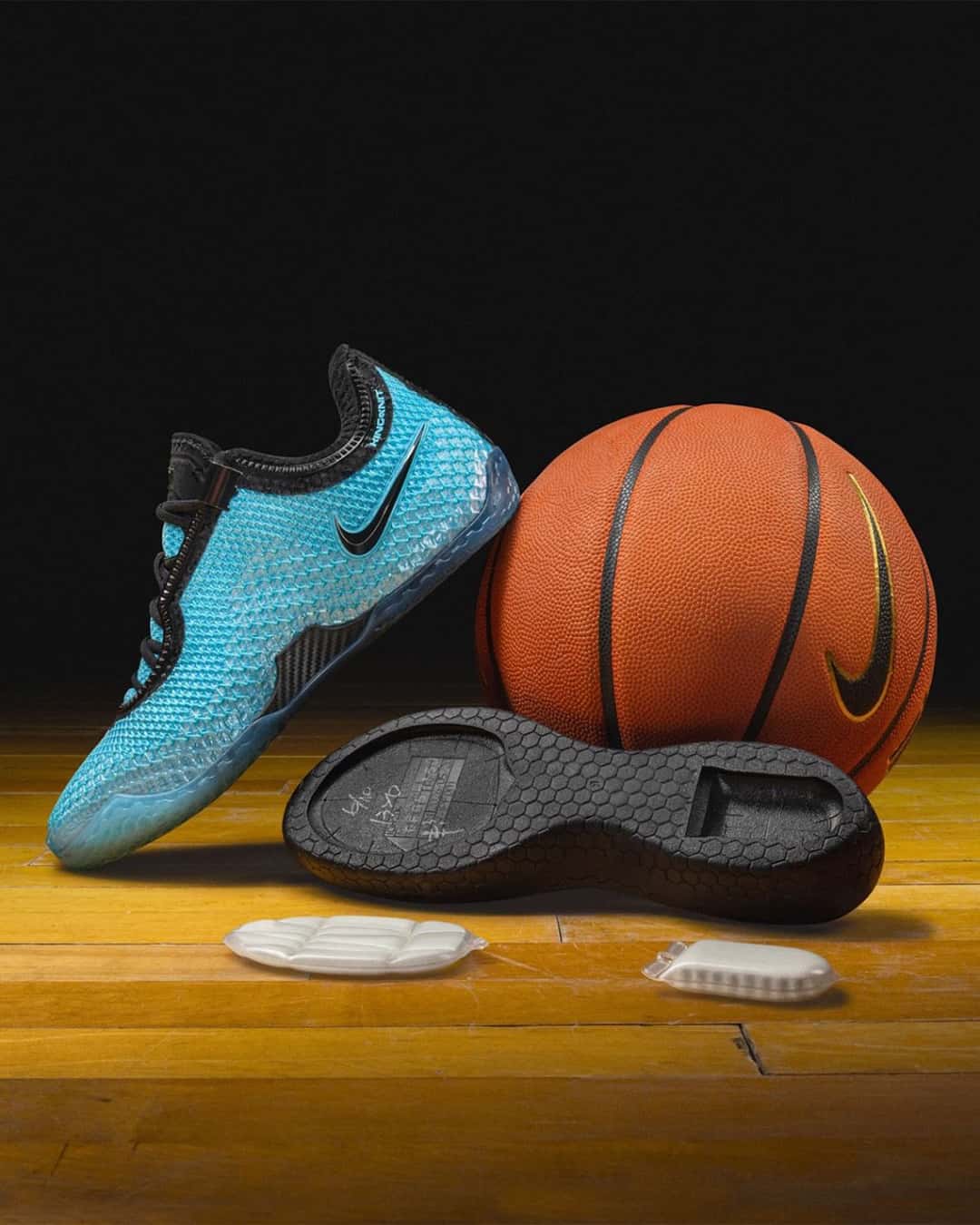 Nike LeBron 24 Stars apoyada junto a una pelota de básquet sobre un piso de parquet, con la plantilla y las unidades de aire al lado