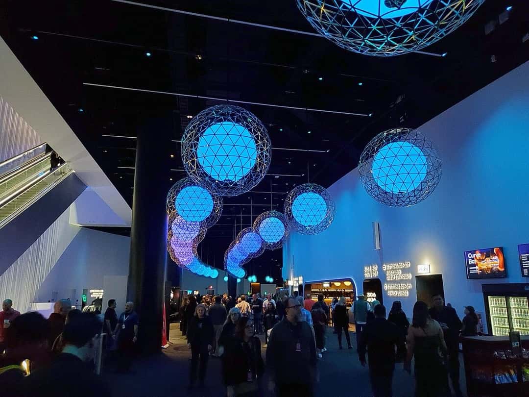 El hall interno de la Sphere de Las Vegas, con esferas de luz azul colgando del techo, escaleras mecánicas a la izquierda y el público caminando hacia las tribunas. Foto: Y2kcrazyjoker4, Wikimedia Commons, CC BY 4.0