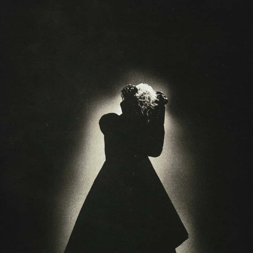 Portada de «Requiem», de keshi: la silueta de una figura con vestido, a contraluz, sobre un fondo negro con un halo de luz blanca