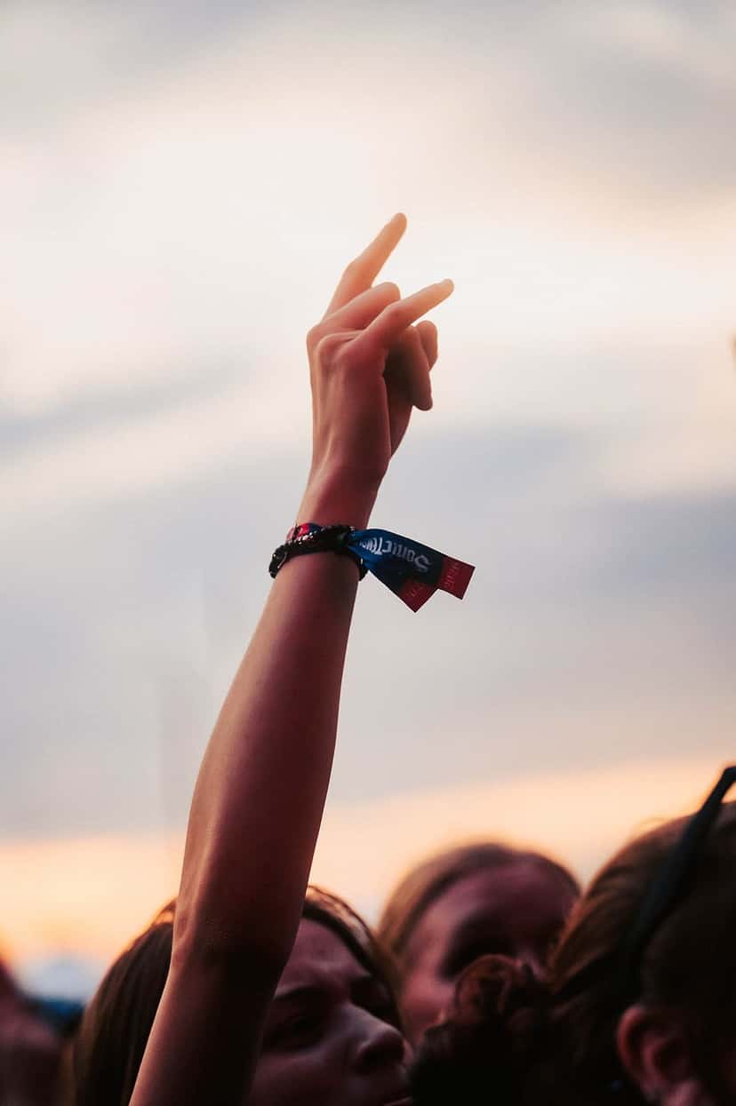 Una fan levanta la mano con la pulsera de tela de Sonic Temple en la muñeca, contra un cielo de atardecer, en la edición 2026 del festival (foto de archivo). Foto: Sonic Temple