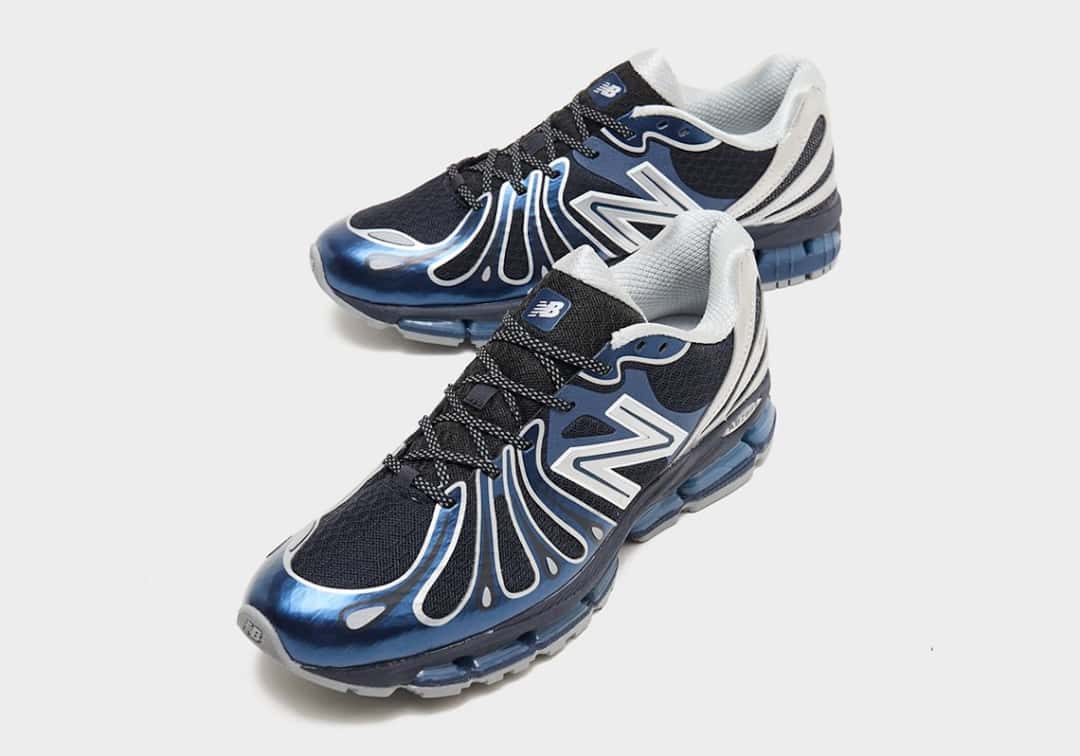 Par de New Balance 1890 Metallic Blue visto en diagonal desde adelante, con los overlays azul metalizado de bordes plateados sobre el mesh negro, cordones negros con puntos blancos, la N plateada y el cuello gris claro