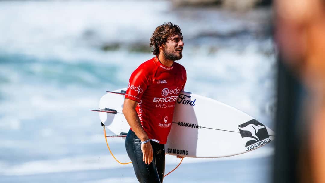 Alonso Correa, con la lycra roja del EDP Ericeira Pro y su tabla blanca bajo el brazo, sale del agua en Ribeira d'Ilhas