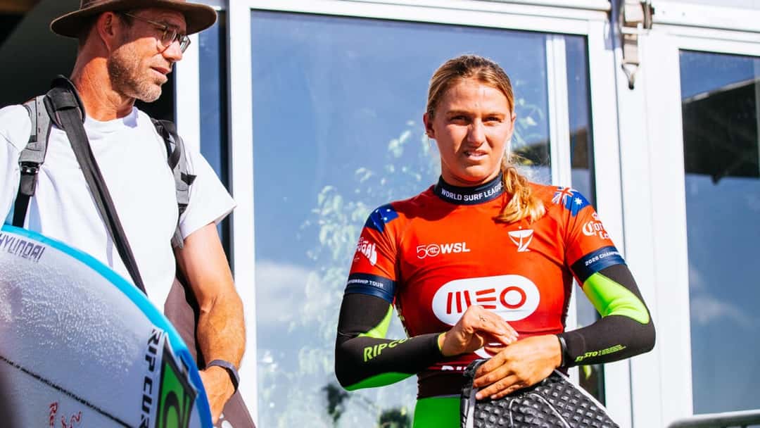 Molly Picklum, con la lycra roja del MEO Rip Curl Pro Portugal y la bandera de Australia en las mangas, escucha a su entrenador junto a la zona de competidores en Supertubos