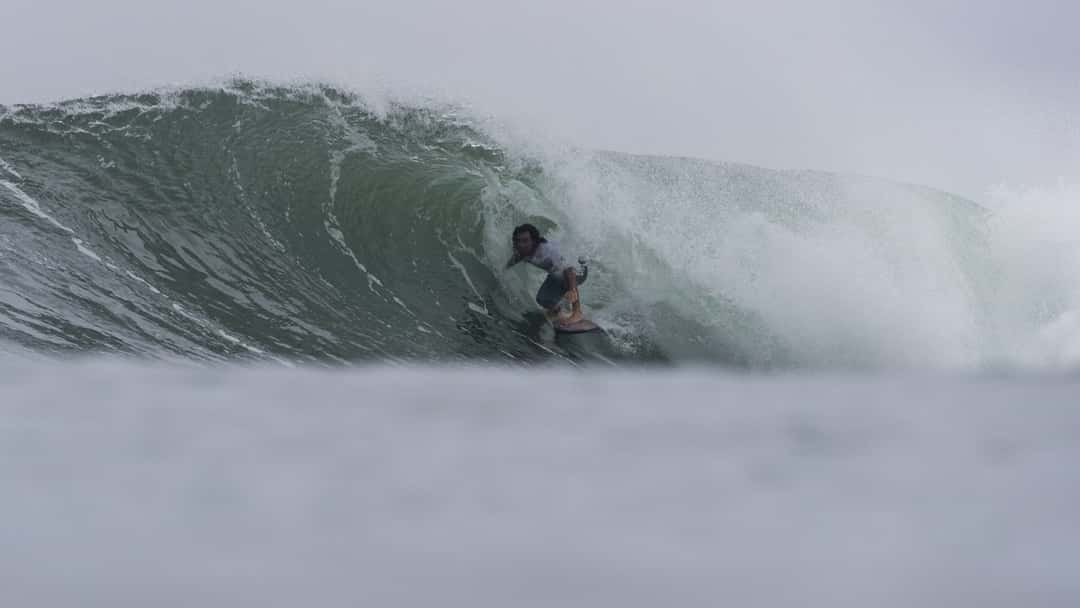 Mason Ho, agachado dentro del tubo de una ola verde de Sunset Beach, bajo la llovizna, el martes 27 de octubre