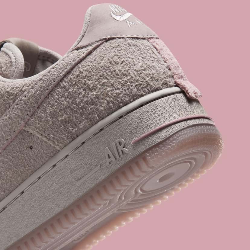 Detalle del talón del Nike Air Force 1 Subway Rat con la tira rosa que imita la cola de una rata, la gamuza gris de pelo largo y la suela translúcida rosa