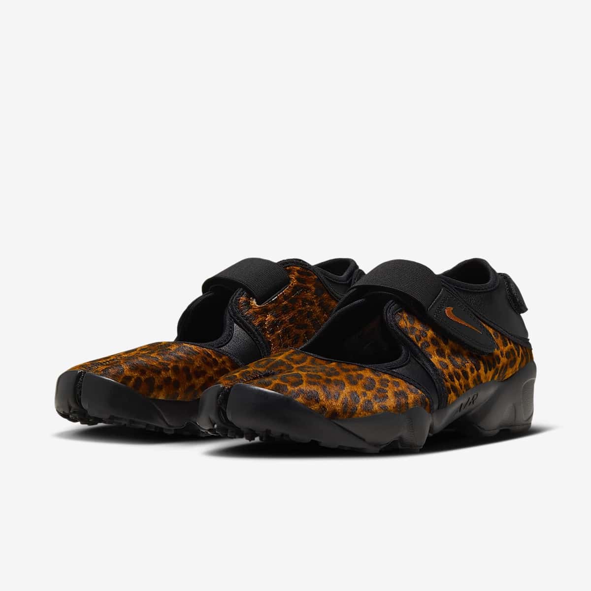 Par del Nike Air Rift Black/Desert Ochre sobre fondo gris claro, con el upper de pelo corto ocre y manchas negras, strap elástico negro con Swoosh ocre, puntera dividida y suela negra