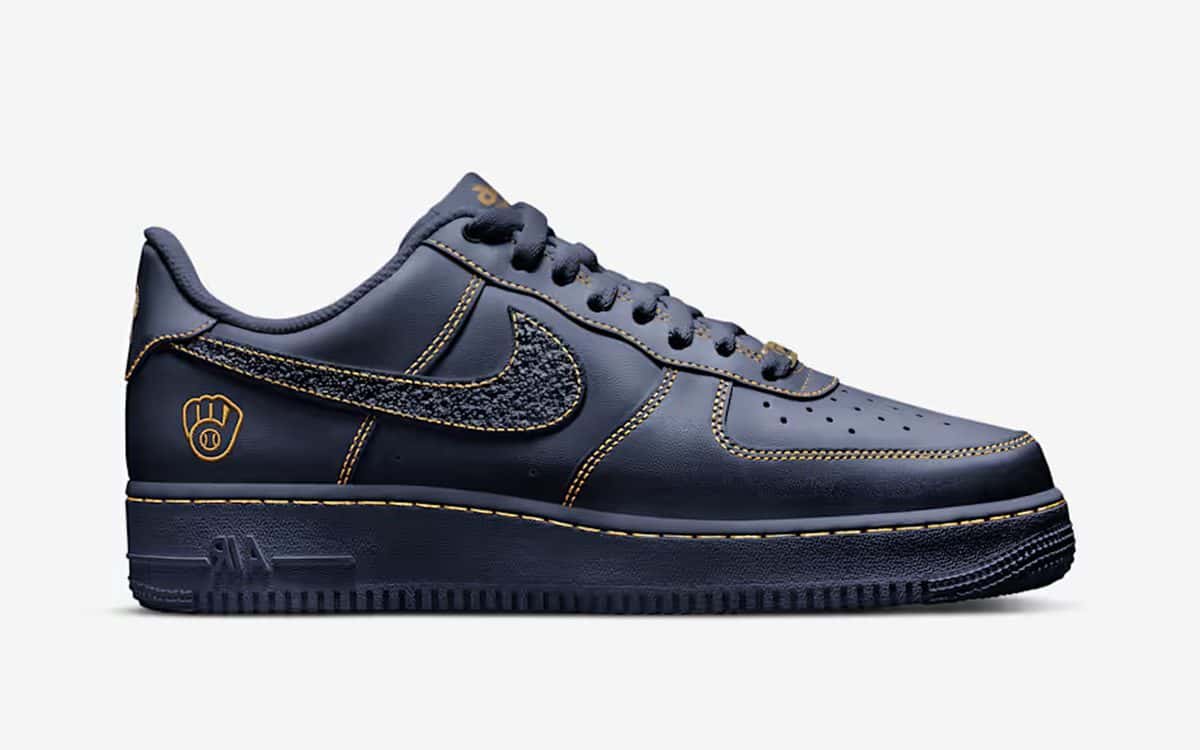 Nike Air Force 1 Low de los Milwaukee Brewers de perfil, en cuero azul marino con costuras doradas, Swoosh texturado y el logo del guante bordado en el talón
