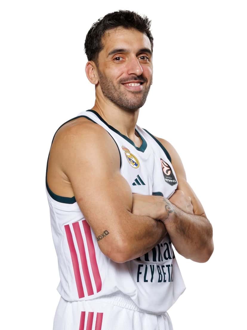Facundo Campazzo, con la camiseta blanca del Real Madrid, posa de brazos cruzados y sonriendo en la foto oficial del plantel