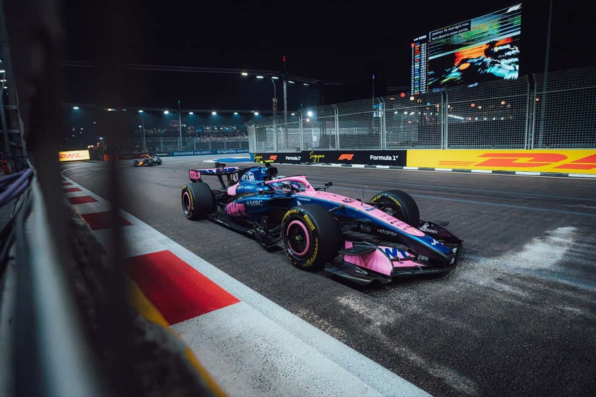 El Alpine número 43 de Franco Colapinto, azul y rosa, dobla de noche pegado al piano en el circuito de Marina Bay durante la carrera