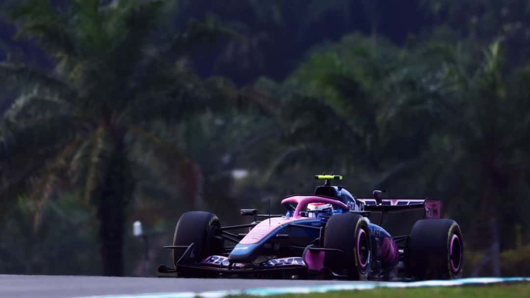 Foto de archivo: el Alpine azul y rosa de Franco Colapinto, de frente, en una curva de Sepang con palmeras de fondo