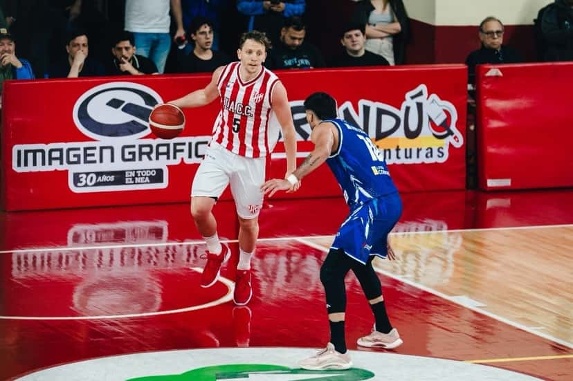 Un jugador de Instituto con la camiseta 5 avanza con la pelota ante la marca de un jugador de Regatas con camiseta azul