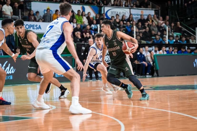 Un jugador de Gimnasia de Comodoro con la camiseta verde 10 avanza con la pelota mientras lo marca un jugador de La Unión de Formosa con camiseta blanca