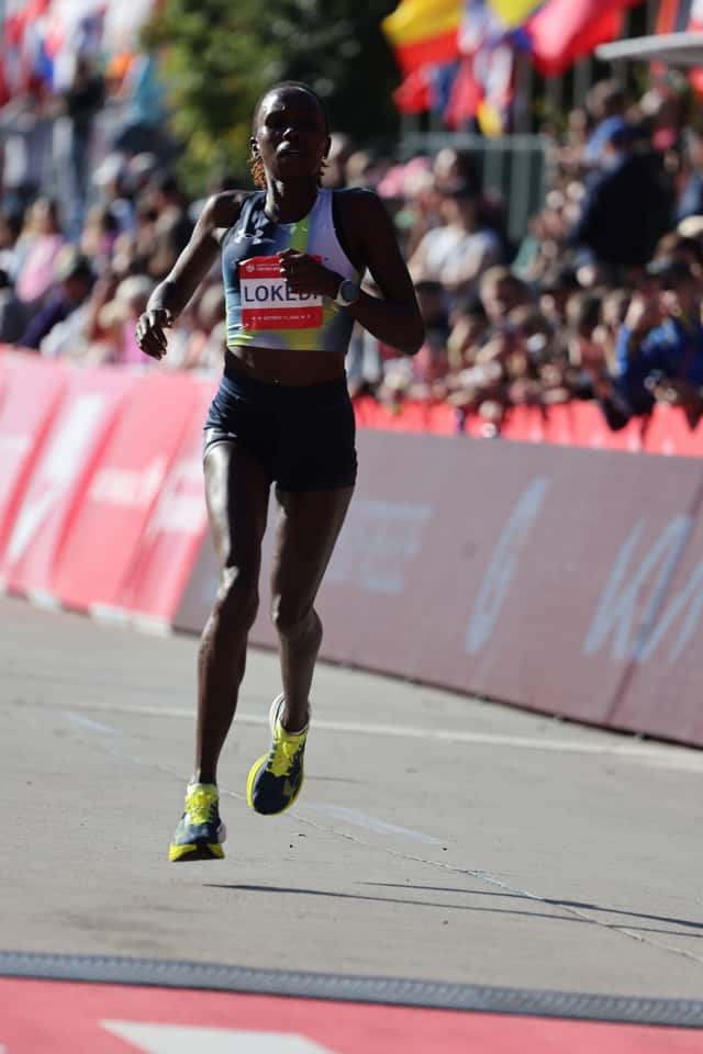 Sharon Lokedi, con top gris y verde y el dorsal con su apellido, corre la recta final del Maratón de Chicago 2026 con el público detrás de las vallas