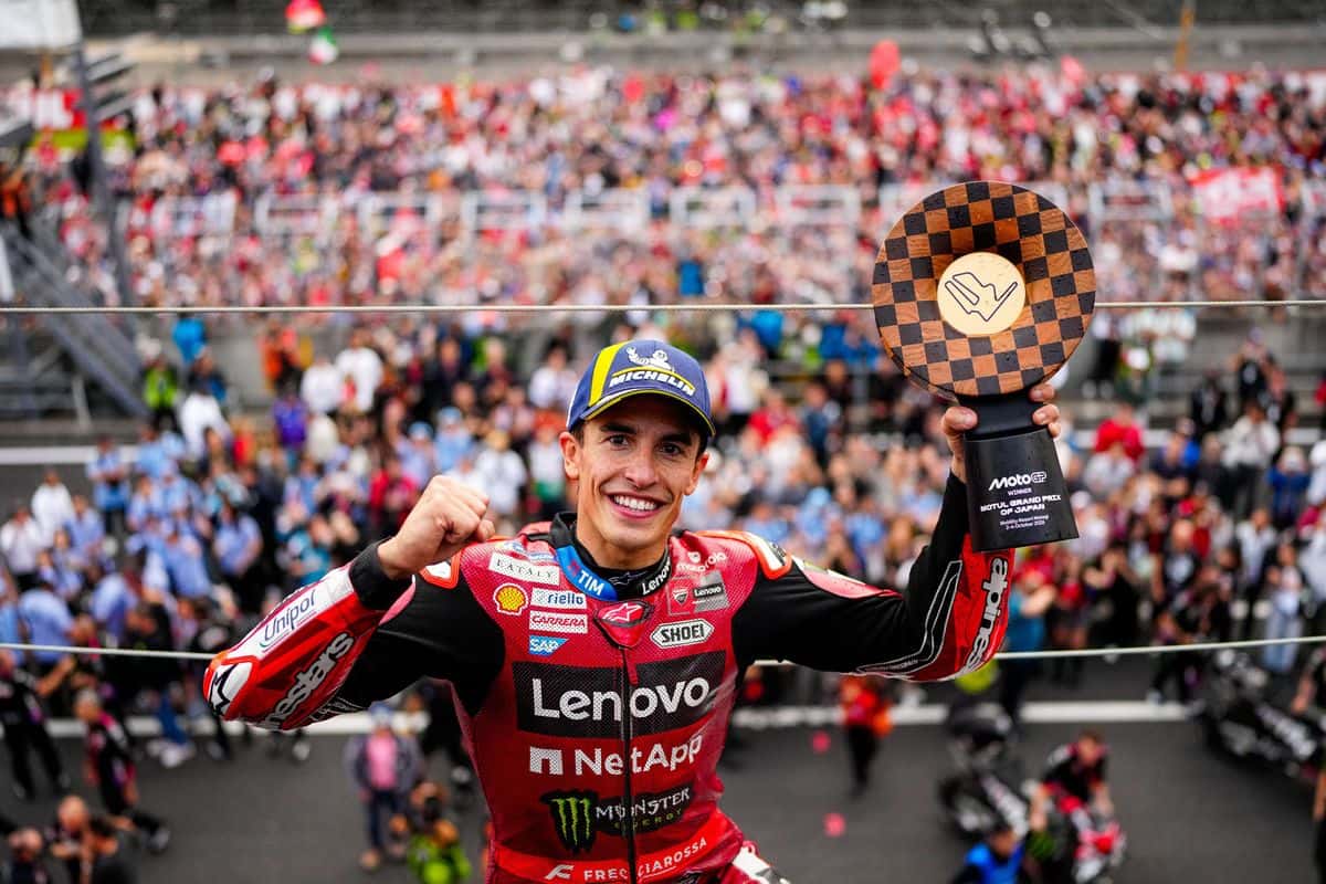 Marc Márquez, con el buzo rojo de Ducati, levanta el trofeo de ganador del Gran Premio de Japón frente a la tribuna de Motegi