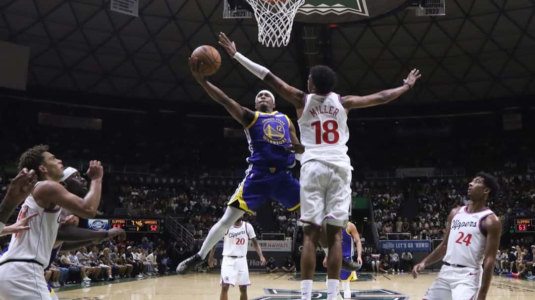 Brandon Williams, con la camiseta azul número 12 de Golden State, va hacia el aro ante la marca de Baba Miller, de los Clippers, en el Stan Sheriff Center de Honolulu