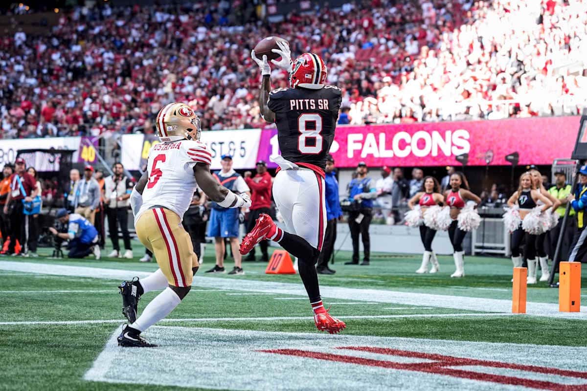 Kyle Pitts, con la camiseta negra número 8 de los Falcons, atrapa en el aire un pase de touchdown en la zona de anotación ante un defensor de los 49ers
