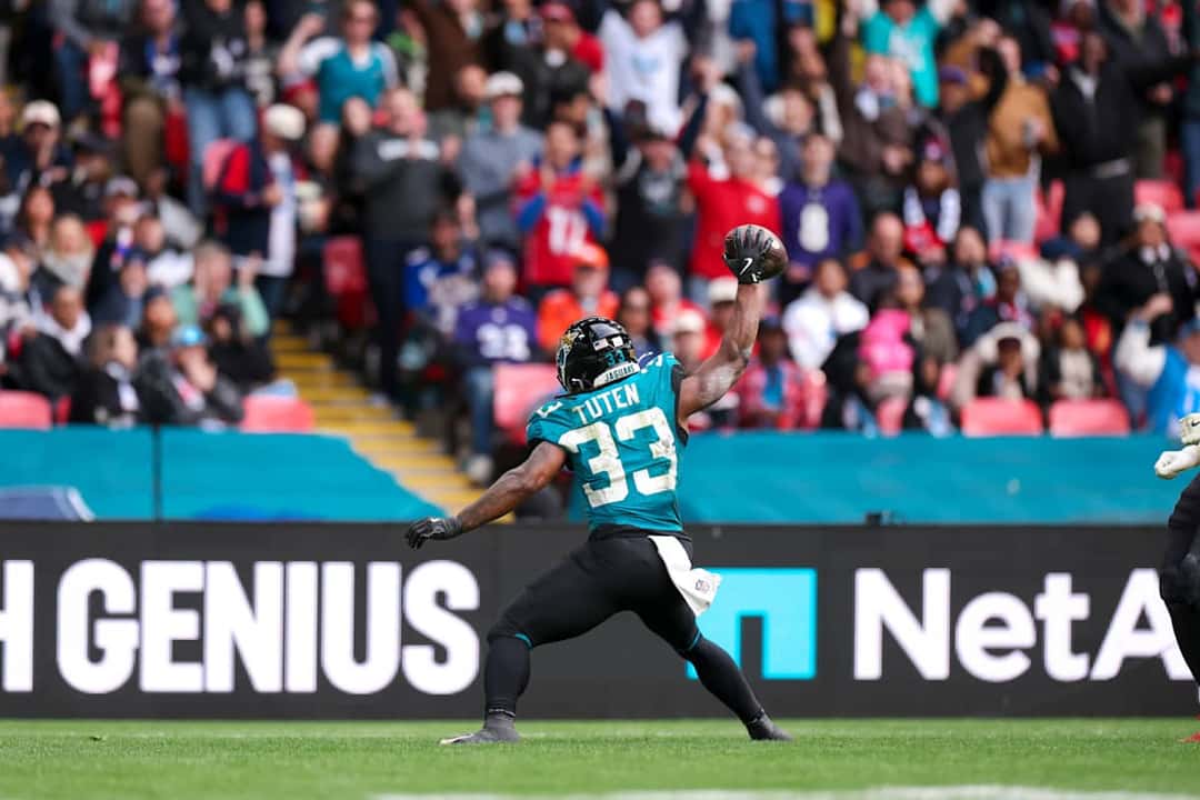 Bhayshul Tuten, con la camiseta turquesa número 33 de los Jaguars, levanta la pelota con la mano derecha delante de la tribuna en Wembley