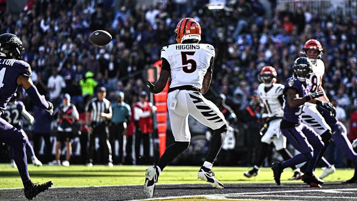 Tee Higgins, con la camiseta blanca número 5 de los Bengals, espera la pelota en el aire para atrapar un pase de touchdown en el estadio de los Ravens