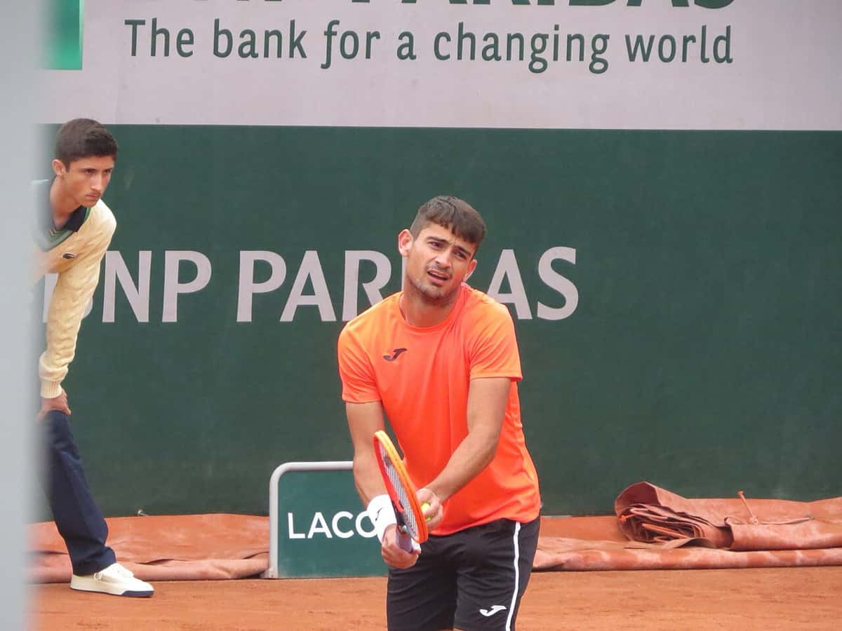 Foto de archivo: Mariano Navone, con remera naranja, espera el saque con la raqueta en las manos en una cancha de polvo de ladrillo de Roland Garros