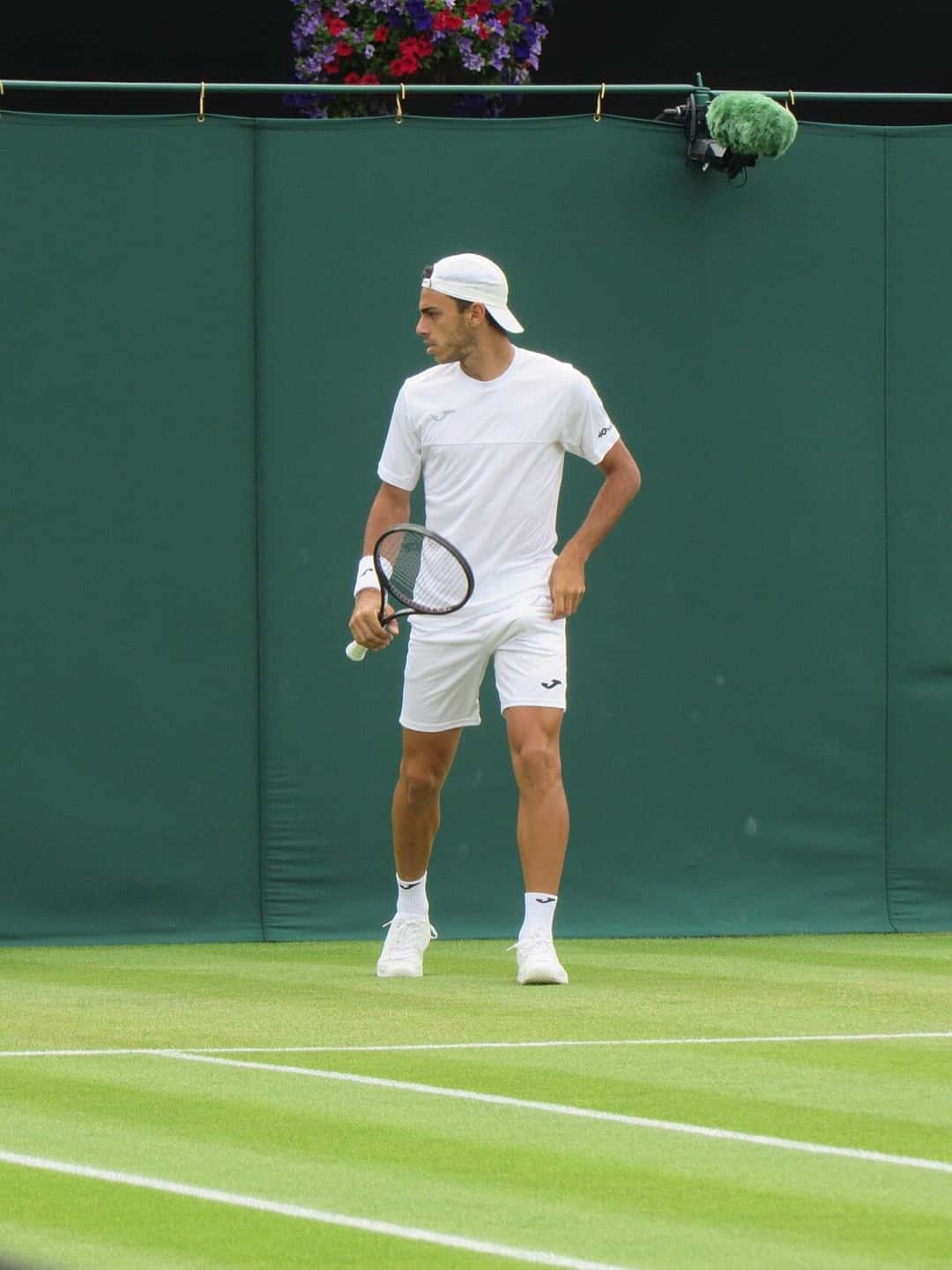 Foto de archivo: Francisco Cerúndolo, de blanco, mira hacia un costado con la raqueta en la mano en una cancha de césped de Wimbledon
