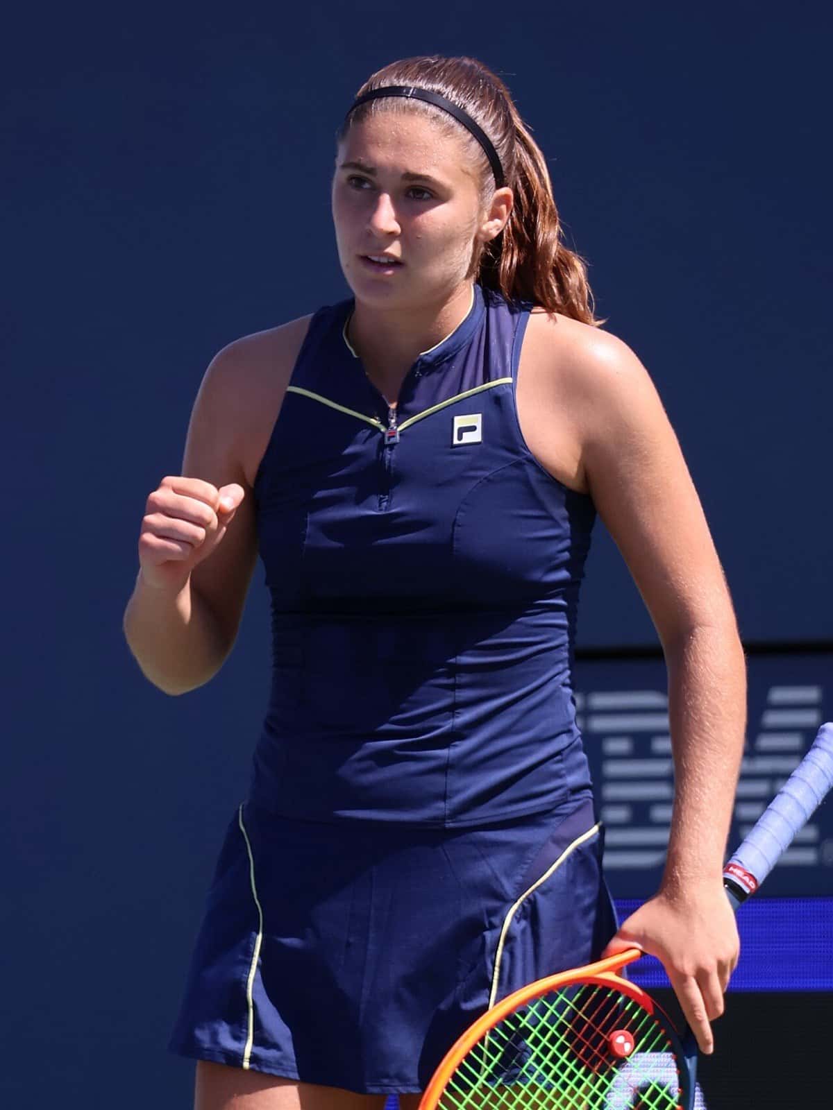 Foto de archivo: Julia Riera, con vestido azul oscuro y vincha, aprieta el puño durante un partido del US Open 2023