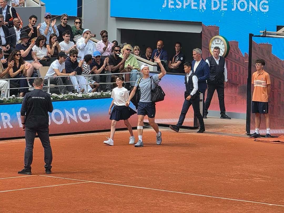 Foto de archivo: Alexander Zverev, con gorra blanca y bolso al hombro, saluda con la mano en alto al entrar a la cancha de Roland Garros 2026, con el público detrás