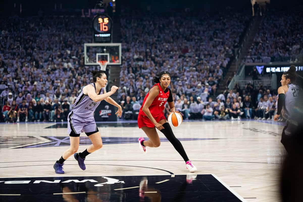 Angel Reese, con la camiseta roja número 5 del Atlanta Dream, avanza con la pelota ante una jugadora de las Valkyries, de violeta, en el Juego 2 de las Finales en el Chase Center