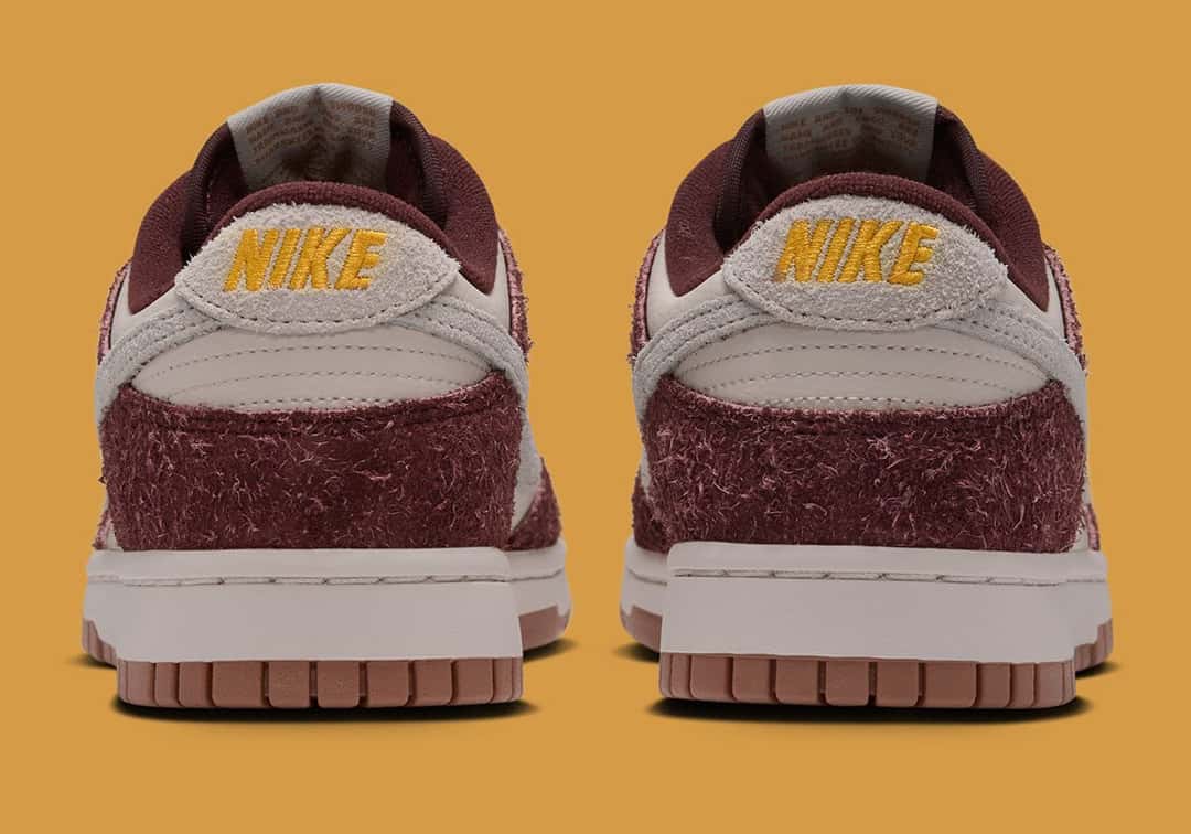 Talones de la Nike Dunk Low Basketball Charm, con el logo Nike bordado en dorado sobre la gamuza bordó y la suela de goma marrón
