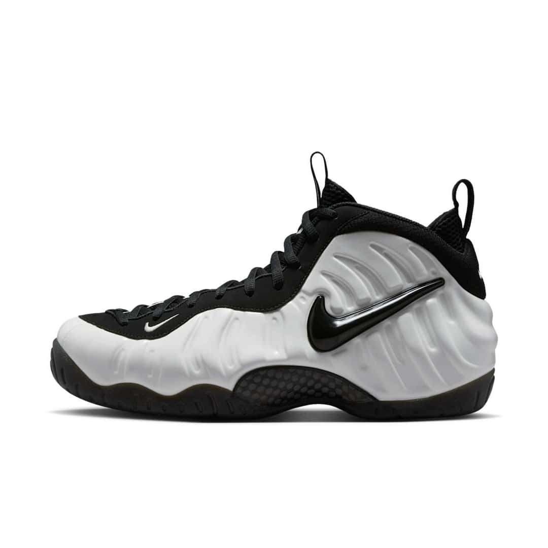 Nike Air Foamposite Pro Premium Summit White de perfil lateral, con la carcasa blanca moldeada, el Swoosh negro tipo joya, la placa de fibra de carbono a la vista y la suela negra