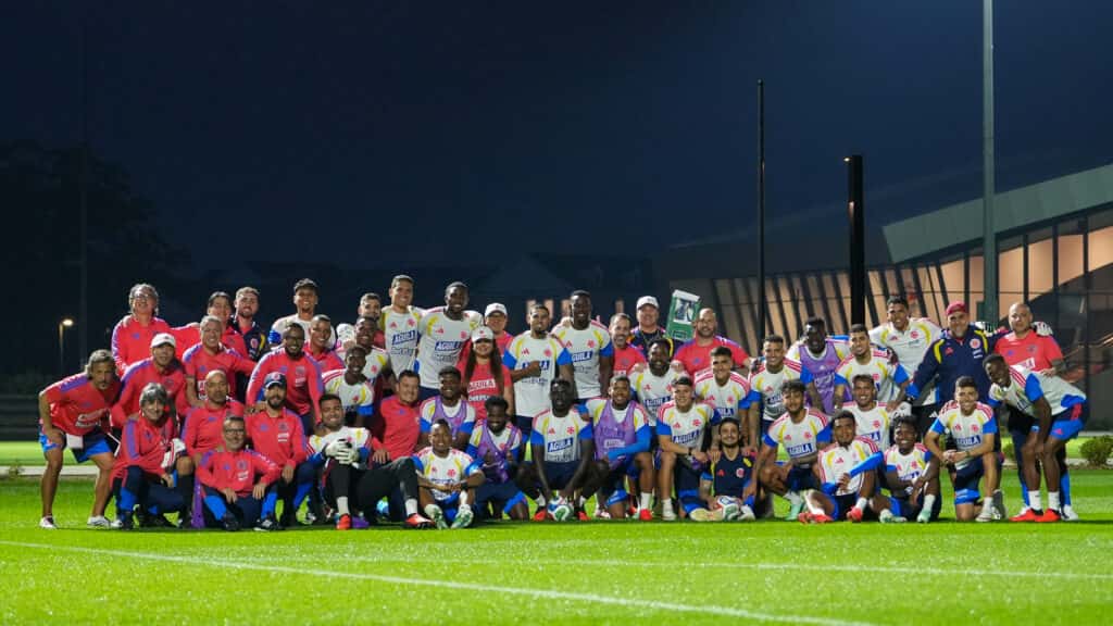 El plantel y el cuerpo técnico de la Selección Colombia posan juntos en una cancha de entrenamiento, de noche