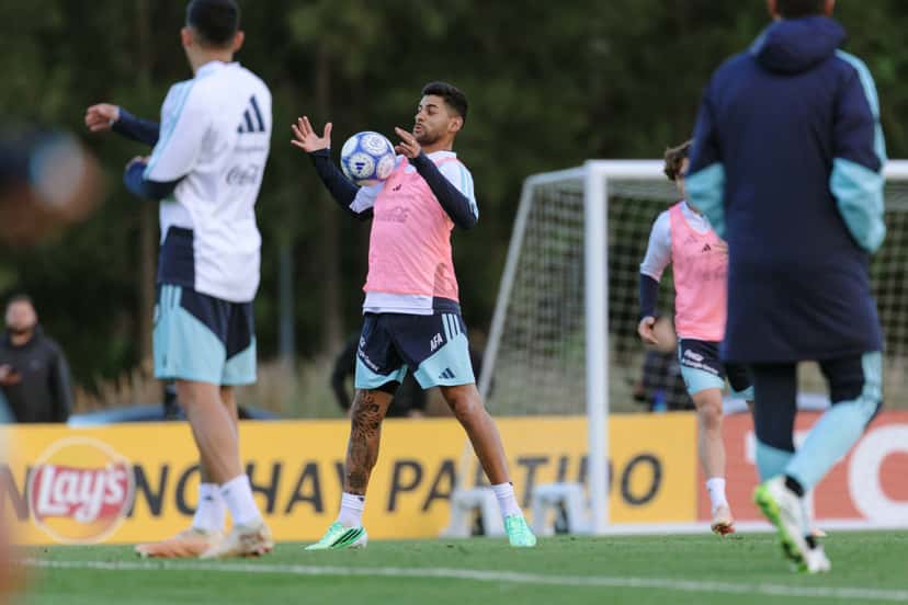 Futbolista de la Selección Argentina con pechera rosa controla la pelota con las manos durante un entrenamiento