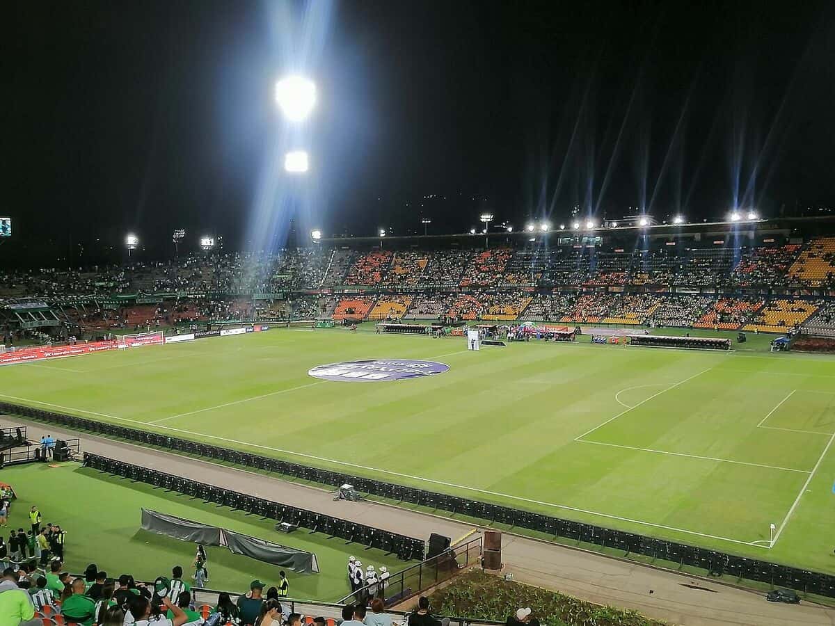 La cancha del estadio Atanasio Girardot, en Medellín, de noche y con las luces encendidas, con hinchas de Atlético Nacional en la tribuna antes de un partido; foto de archivo de agosto de 2025 (foto: User34790, Wikimedia Commons, licencia CC BY-SA 4.0)
