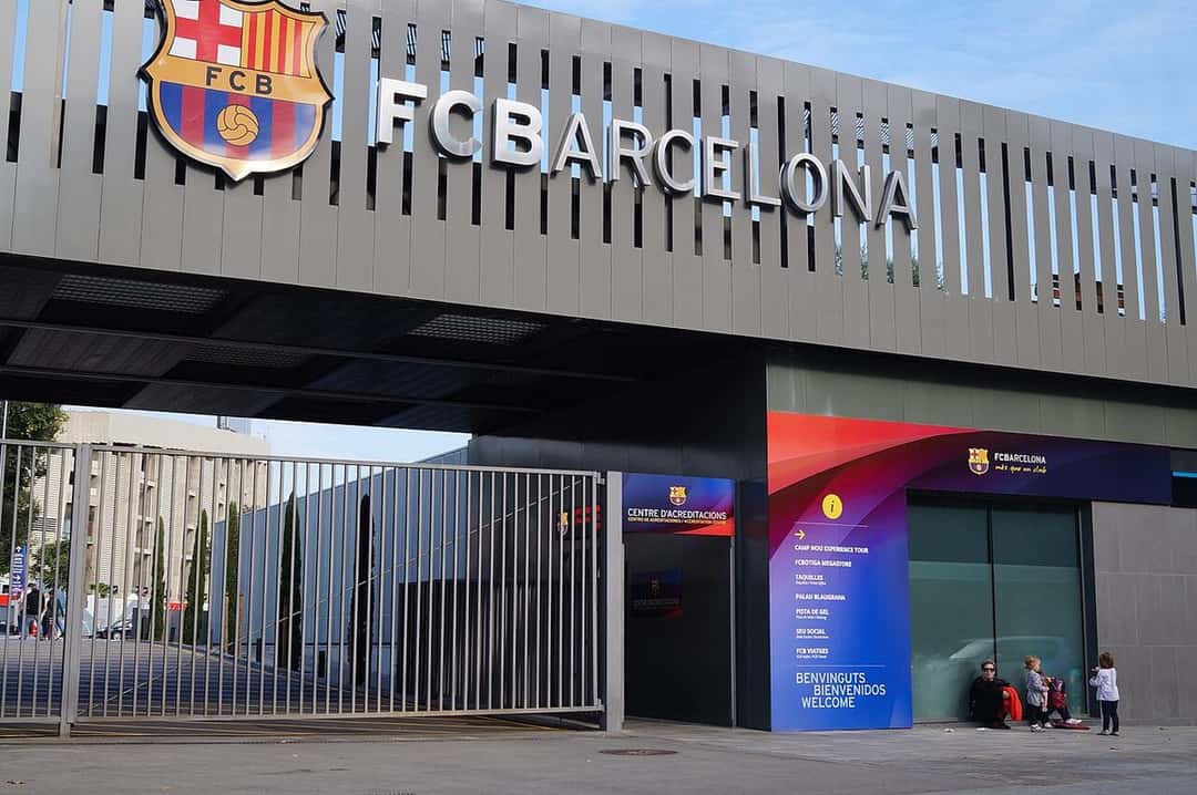 La entrada del Spotify Camp Nou, con el escudo y el nombre del FC Barcelona sobre la fachada gris y los carteles de bienvenida; foto de archivo de octubre de 2015 (foto: Roxymatic, Wikimedia Commons, licencia CC BY-SA 4.0)
