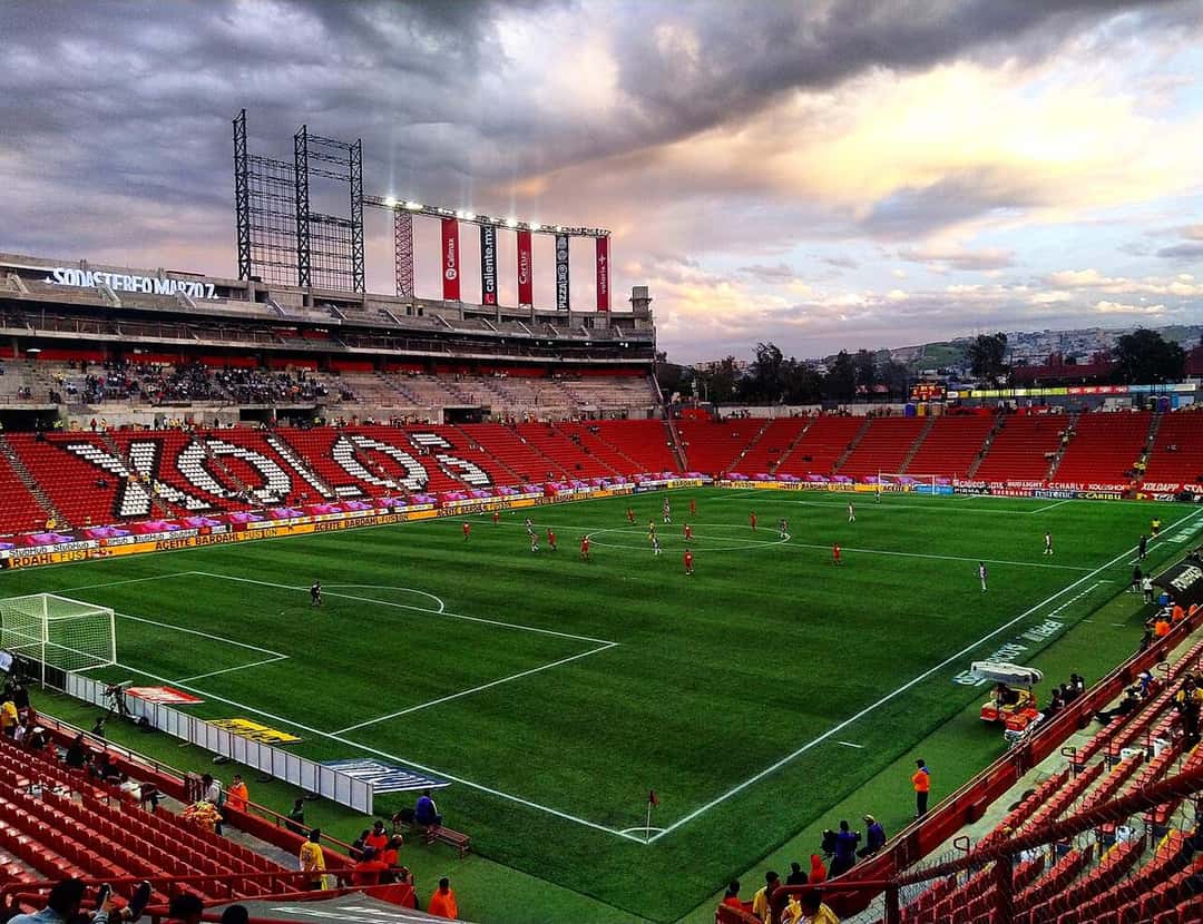 El estadio Caliente, de Tijuana, con la palabra «Xolos» escrita en las butacas de la tribuna y el partido en juego; foto de archivo de 2020 (foto: Chiko elektriko, Wikimedia Commons, licencia CC BY-SA 4.0)
