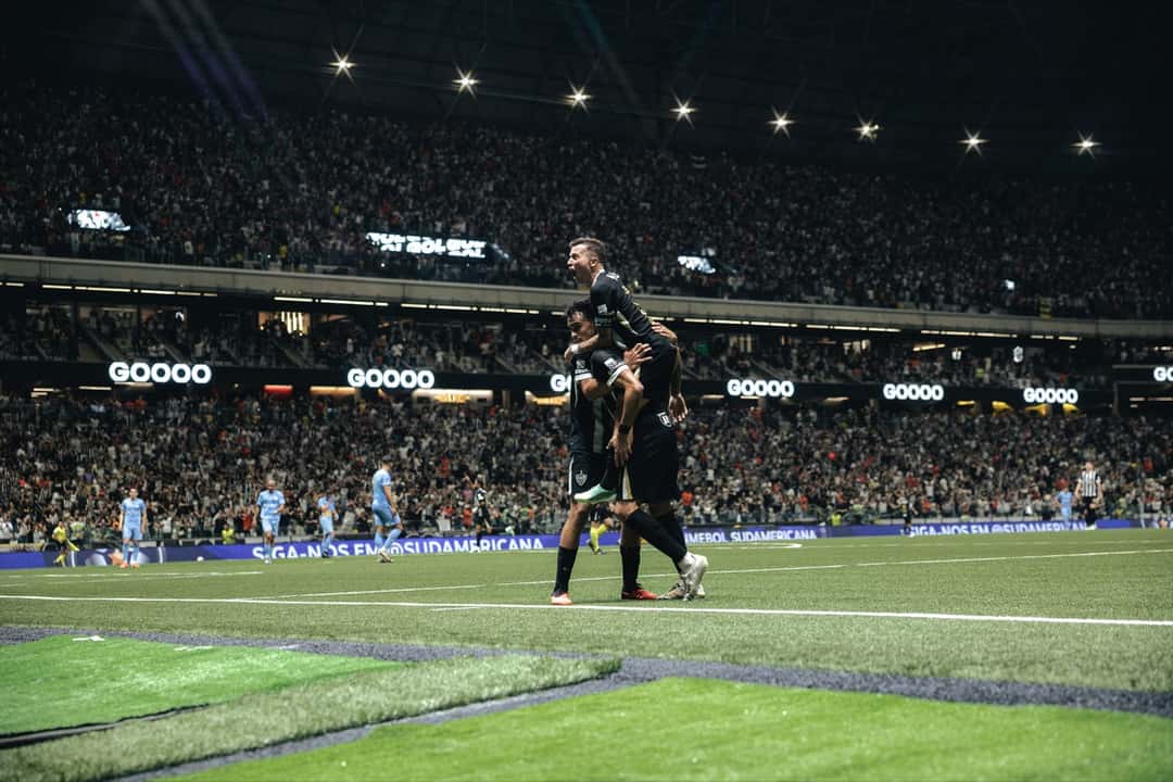 Dos jugadores de Atlético Mineiro, uno subido a la espalda del otro, festejan un gol junto a la línea de fondo mientras los futbolistas de Montevideo City Torque, de celeste, vuelven al medio con la Arena MRV llena de fondo (foto: Pedro Souza / prensa oficial de Atlético Mineiro)