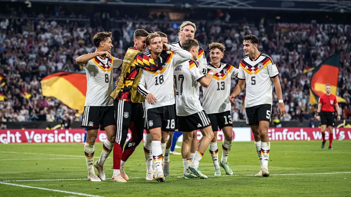 Los jugadores de Alemania, con la camiseta blanca, festejan un gol ante Serbia en el estadio de Múnich, con banderas alemanas en la tribuna