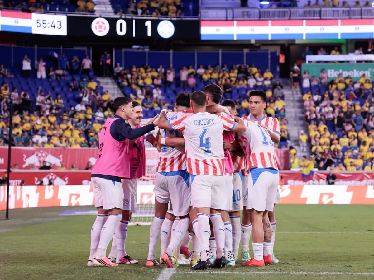 Los jugadores de Paraguay se abrazan tras el gol ante Colombia en el Sports Illustrated Stadium, con el marcador 0-1 en la pantalla