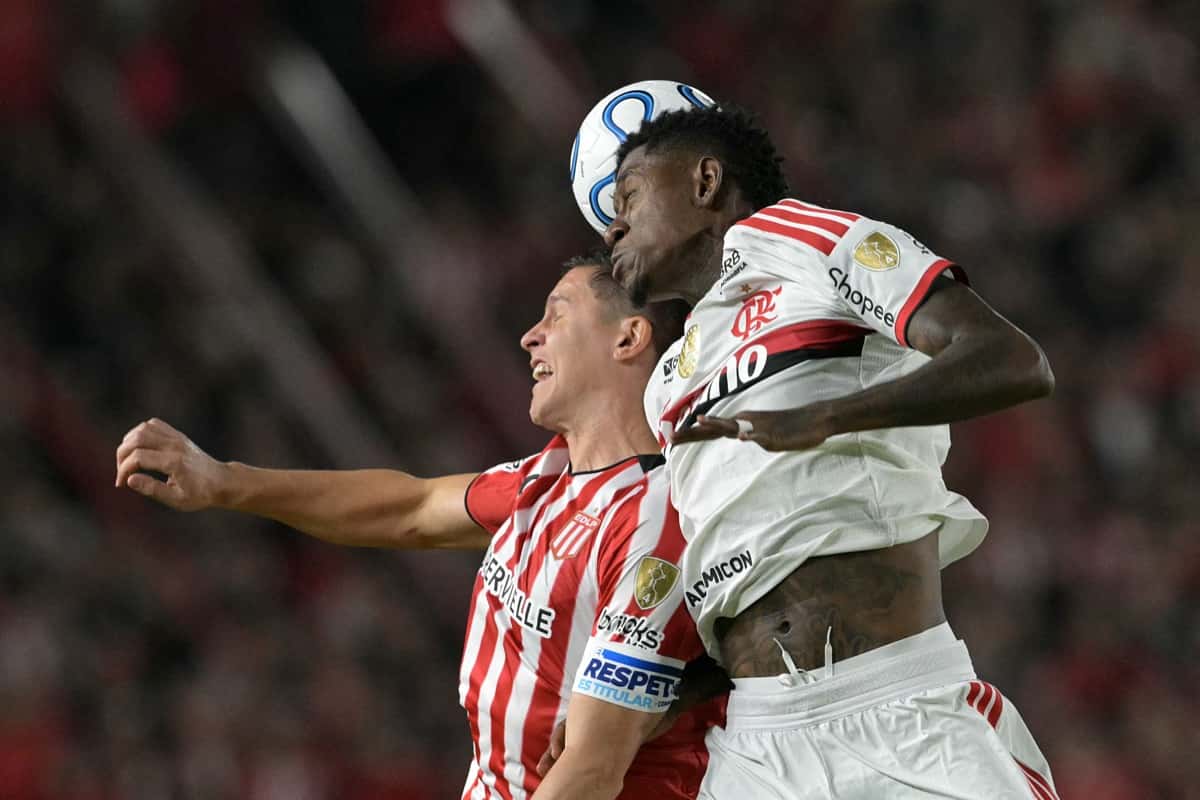 Un jugador de Estudiantes y uno de Flamengo saltan a cabecear la misma pelota en un cruce de la Copa Libertadores