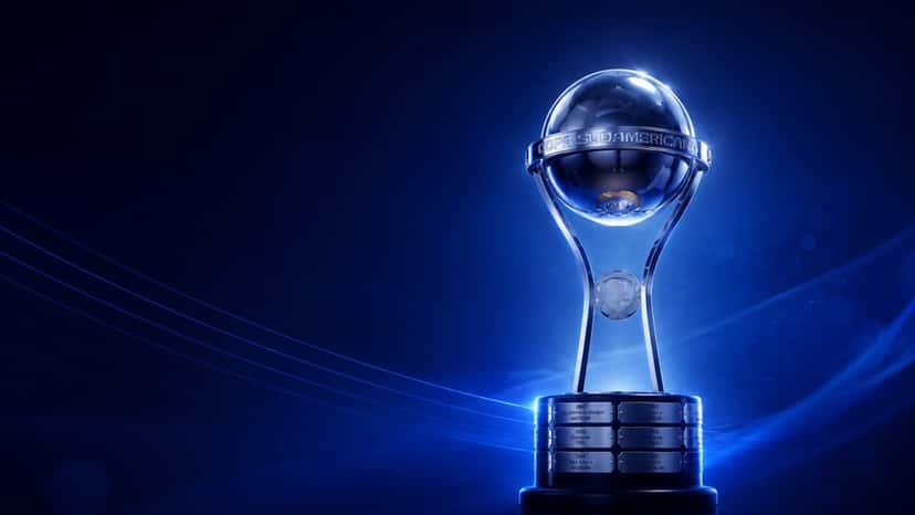 El trofeo de la CONMEBOL Sudamericana iluminado sobre un fondo azul