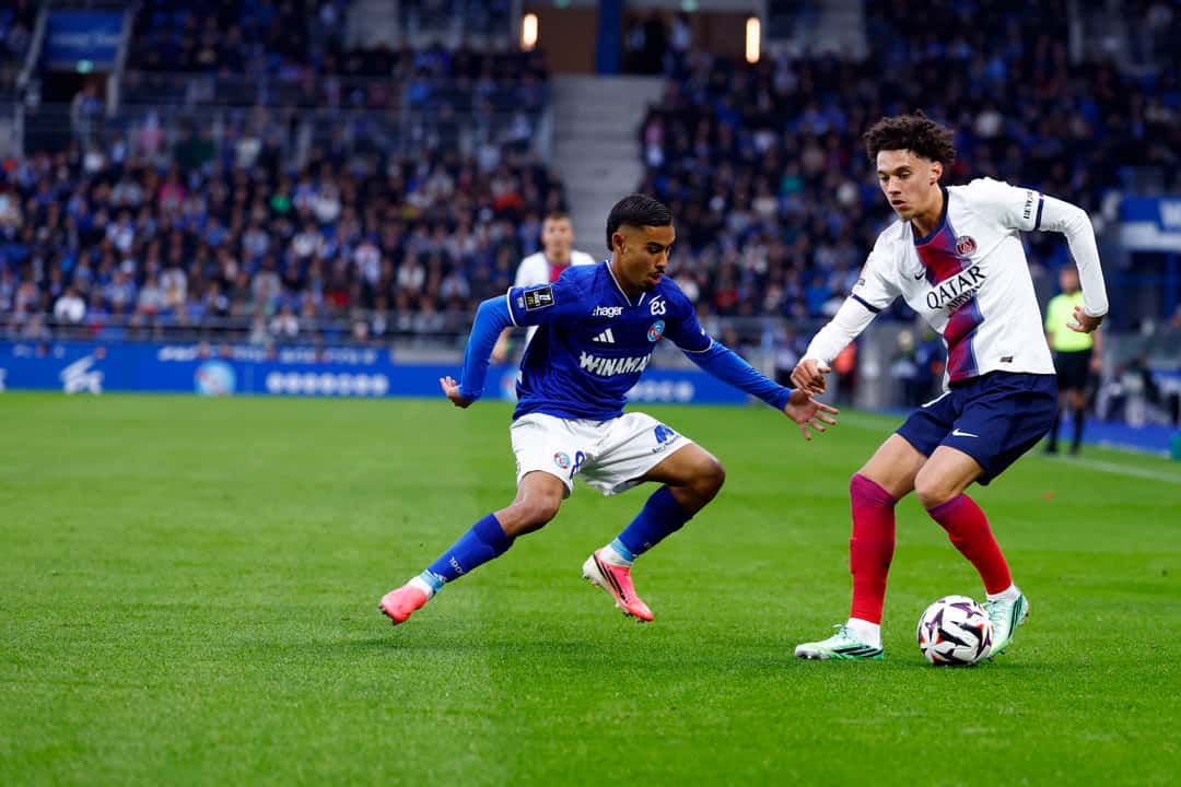Un jugador del Strasbourg, con camiseta azul y pantalón blanco, intenta cortar a un jugador del PSG, de camiseta blanca, que conduce la pelota en La Meinau (foto: prensa Paris Saint-Germain)