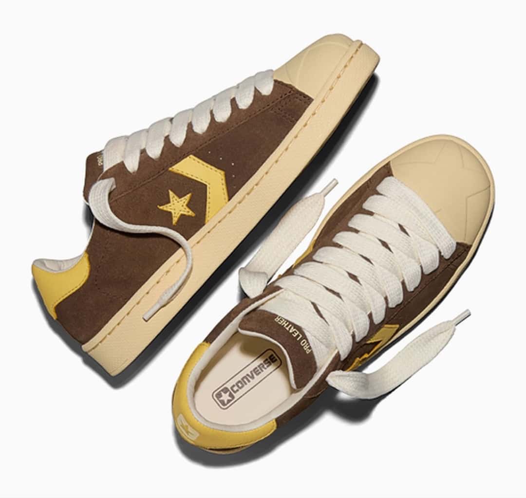 Par de Converse Pro Leather Bison de GOLF le FLEUR* visto desde arriba sobre fondo blanco, en gamuza marrón con la estrella, el chevron y el talón amarillos, cordones gruesos color crudo y la plantilla con el logo de Converse