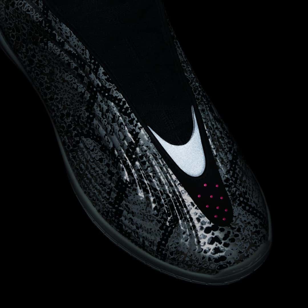 Primer plano de la punta de la adidas Harden Vol. 10 Snakeskin sobre fondo negro, con la pieza reflectiva del centro brillando en blanco, el estampado de víbora oscurecido y una hilera de puntos rosas